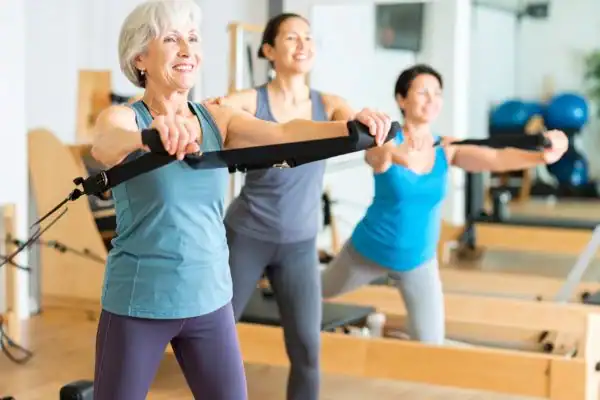 Toning Arms After 60: Empowering Womens Fitness Through Effective Weight Training 2 older woman doing weight training Stowmarket and resistance in the gym to tone upper arms